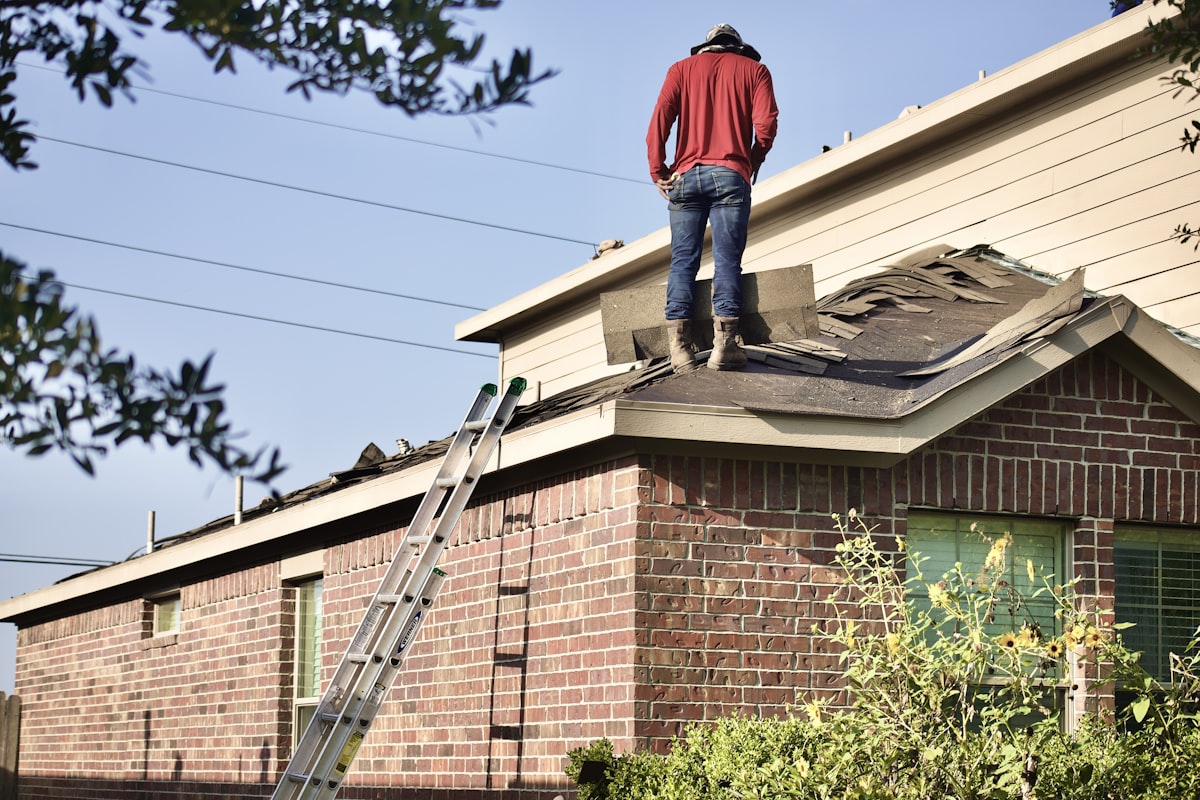Roofer inspecting storm damage on a brick home